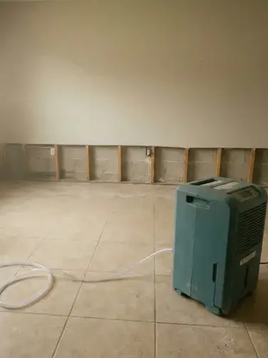 Dehumidifier and air movers drying a tiled room after a flood cut