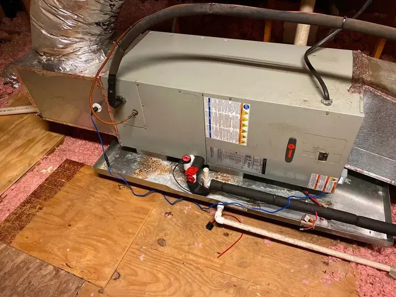 Attic air handler sitting in its drain pan on plywood over insulation