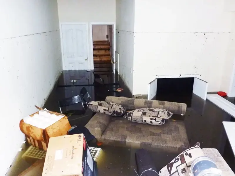 Furniture and boxes sitting in standing water in a flooded basement